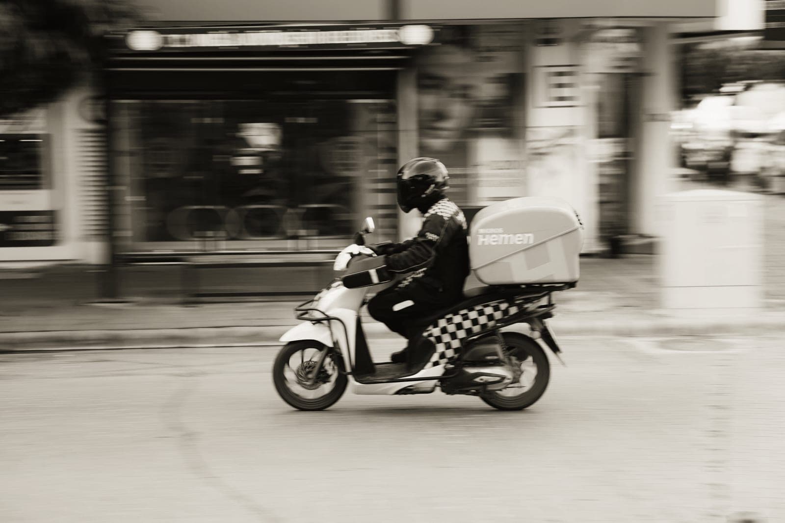 A rider on a seated electric moped-style scooter on a street